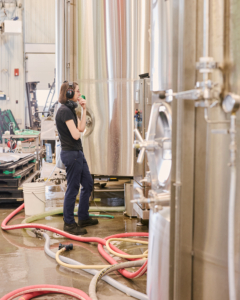 Woman cleaning brewing tanks at a craft brewery.